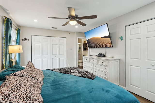 bedroom featuring ceiling fan, two closets, hardwood / wood-style floors, and ensuite bathroom