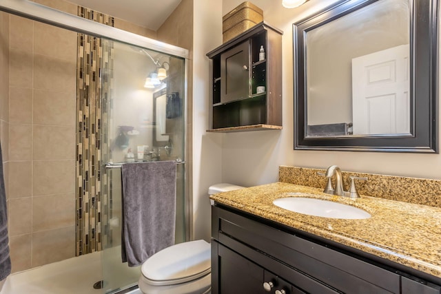 bathroom featuring toilet, vanity, and a shower with shower door