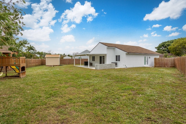 back of house with a playground, a storage shed, a lawn, and a patio