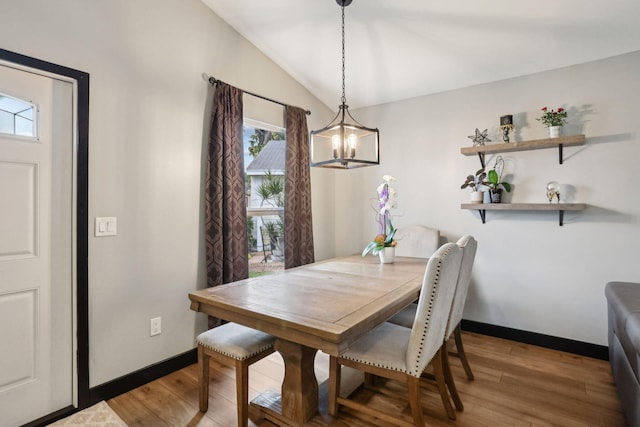 dining space with lofted ceiling, wood-type flooring, and a chandelier