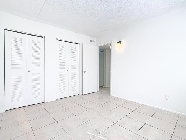 Xx Michigan Court, Saint Cloud, FL 34769 - unfurnished bedroom featuring light tile patterned floors, visible vents, two closets, and a textured ceiling