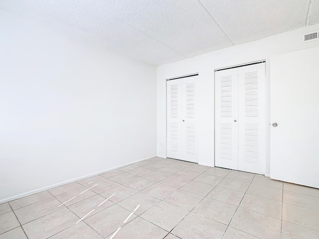 Xx Michigan Court, Saint Cloud, FL 34769 - unfurnished bedroom featuring visible vents, multiple closets, a textured ceiling, light tile patterned floors, and baseboards