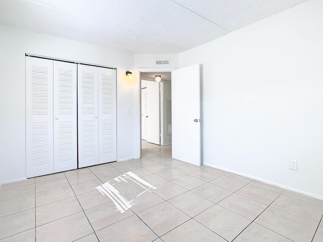 unfurnished bedroom featuring light tile patterned floors, visible vents, a closet, and a textured ceiling