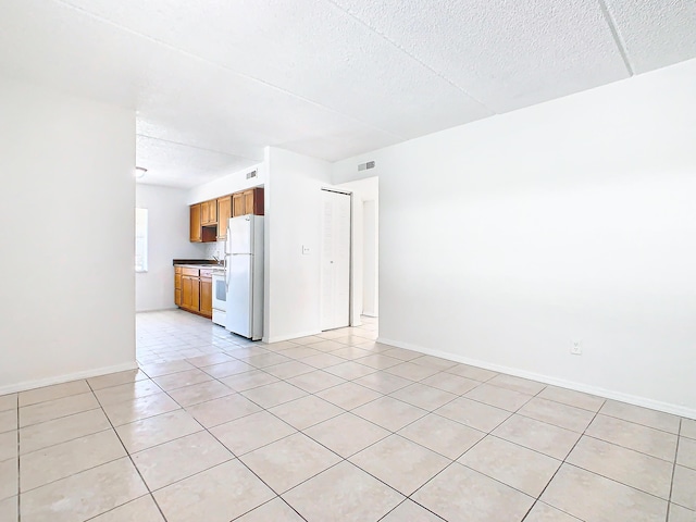 unfurnished living room with light tile patterned floors, visible vents, baseboards, and a textured ceiling