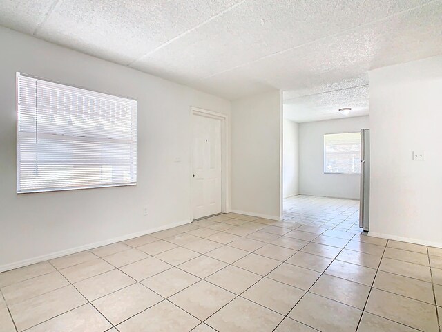 Xx Michigan Court, Saint Cloud, FL 34769 - spare room featuring light tile patterned floors, baseboards, and a textured ceiling