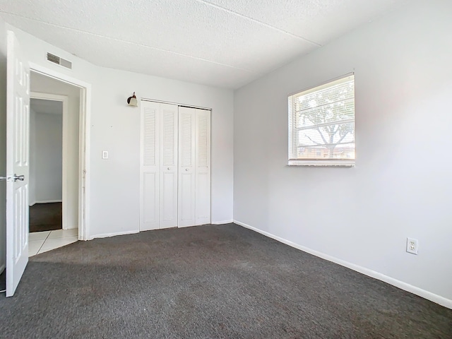 unfurnished bedroom featuring baseboards, visible vents, a closet, a textured ceiling, and carpet flooring