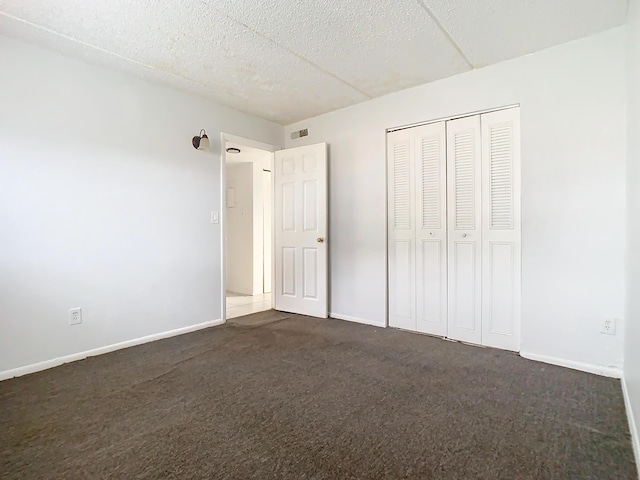 unfurnished bedroom with visible vents, baseboards, and dark carpet