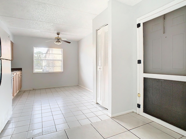 interior space with light tile patterned flooring, a textured ceiling, and a ceiling fan