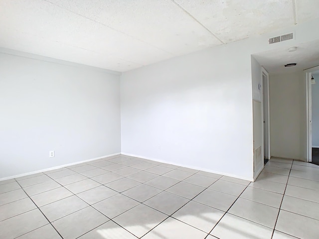 empty room with light tile patterned floors, visible vents, and baseboards