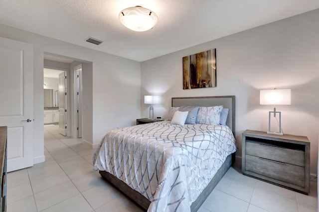 bedroom with ensuite bathroom and a textured ceiling