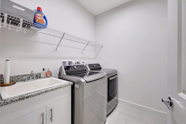 washroom with sink, cabinets, washing machine and dryer, and light tile patterned floors