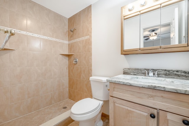 bathroom with toilet, a tile shower, ceiling fan, and vanity