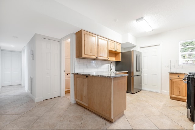 kitchen with light stone countertops, light tile patterned floors, decorative backsplash, and high end refrigerator