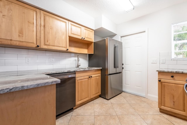 kitchen with light stone counters, decorative backsplash, appliances with stainless steel finishes, light tile patterned flooring, and sink