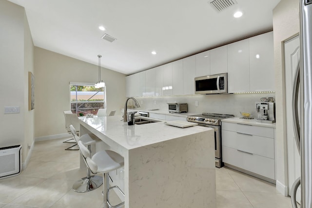 kitchen with appliances with stainless steel finishes, hanging light fixtures, white cabinetry, and sink