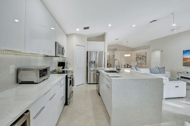 kitchen with white cabinetry, a kitchen island with sink, vaulted ceiling, and appliances with stainless steel finishes