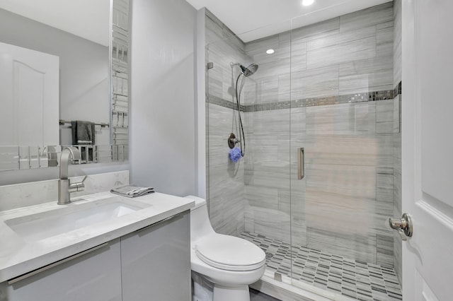 bathroom with toilet, a shower with door, and vanity