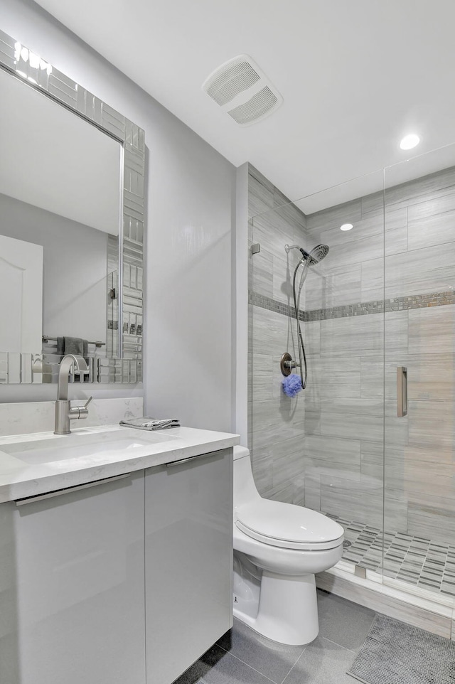 bathroom with toilet, tile patterned flooring, a shower with shower door, and vanity