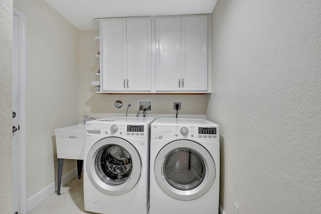 washroom featuring washing machine and dryer, light tile patterned floors, and cabinets