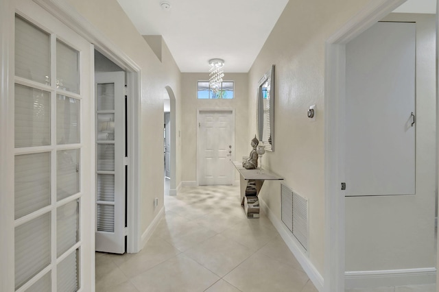 corridor with an inviting chandelier and light tile patterned flooring