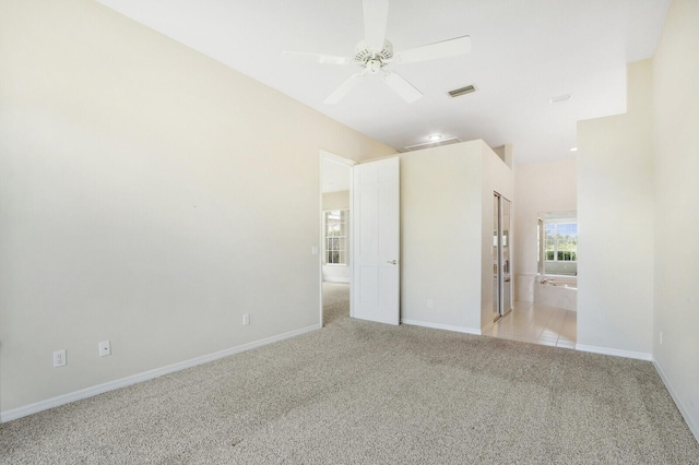 unfurnished bedroom with ceiling fan, light colored carpet, and ensuite bathroom