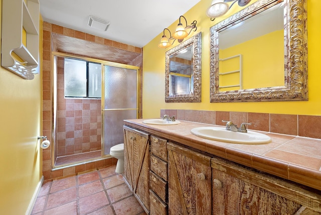 bathroom featuring vanity, toilet, and a shower with shower door