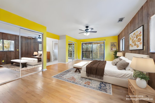 bedroom with access to outside, wood walls, ceiling fan, and light hardwood / wood-style flooring