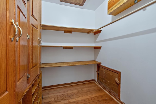 walk in closet with built in desk and light hardwood / wood-style flooring