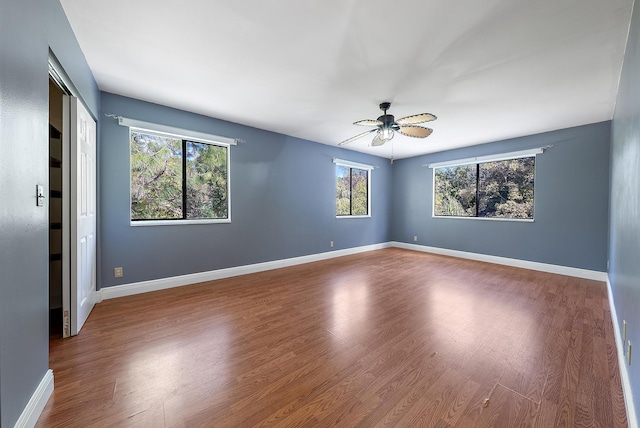 empty room with ceiling fan, hardwood / wood-style floors, and a wealth of natural light