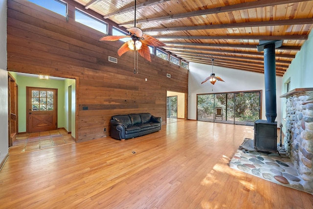 unfurnished living room featuring ceiling fan, a wood stove, wood ceiling, and high vaulted ceiling