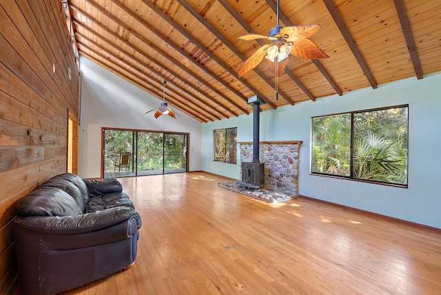 unfurnished living room featuring high vaulted ceiling, a wood stove, wooden ceiling, and beam ceiling