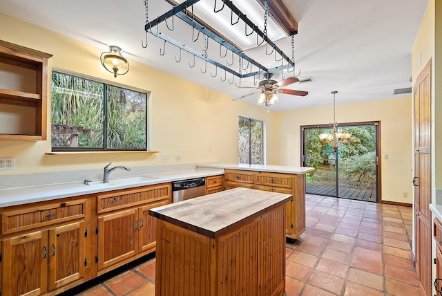 kitchen with sink, wooden counters, stainless steel dishwasher, a kitchen island, and pendant lighting