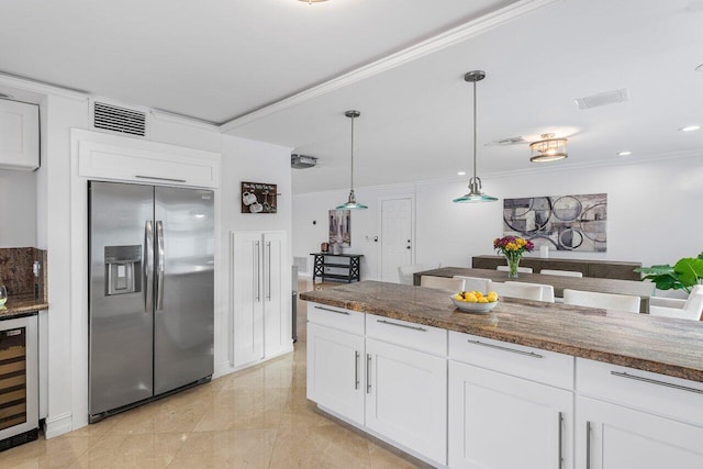 kitchen featuring beverage cooler, stainless steel fridge with ice dispenser, dark stone counters, white cabinetry, and decorative light fixtures