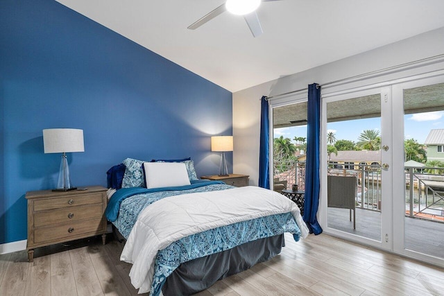 bedroom with wood-type flooring, access to exterior, ceiling fan, and a water view