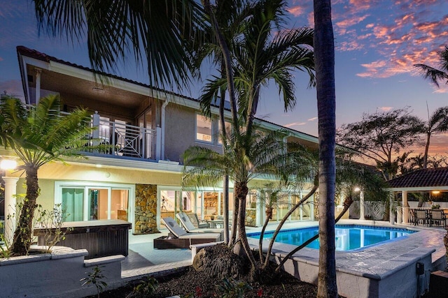 pool at dusk featuring an outdoor hangout area