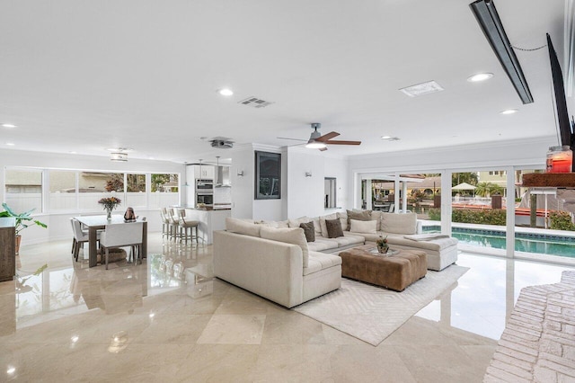 living room featuring ceiling fan, crown molding, and plenty of natural light