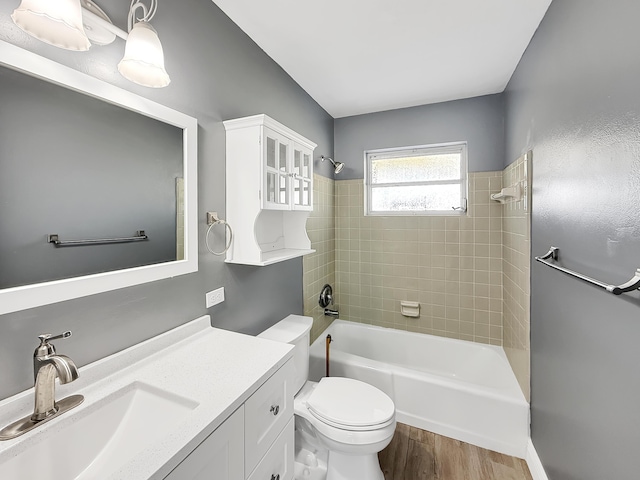 full bathroom with toilet, tiled shower / bath combo, wood-type flooring, and vanity