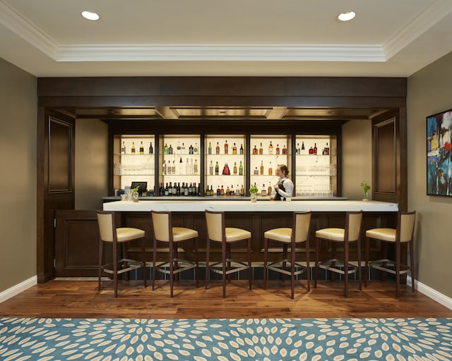 bar featuring dark hardwood / wood-style flooring, crown molding, and a tray ceiling