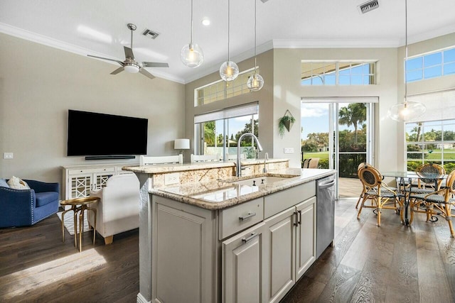 kitchen featuring light stone countertops, sink, hanging light fixtures, and a kitchen island with sink