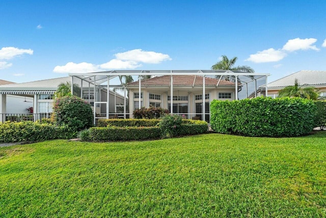 rear view of property with a lanai and a yard