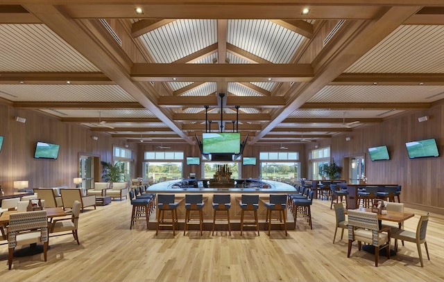 dining space with beam ceiling, a healthy amount of sunlight, and light hardwood / wood-style flooring