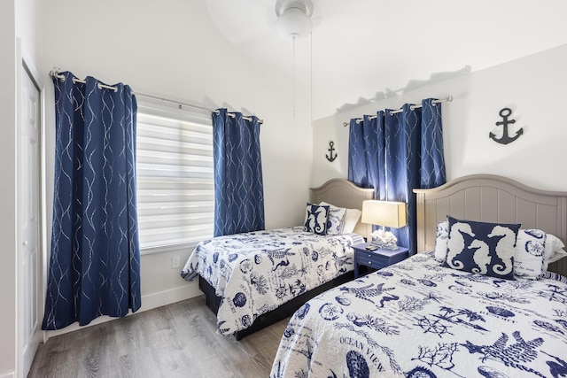 bedroom featuring ceiling fan, a closet, multiple windows, and hardwood / wood-style floors