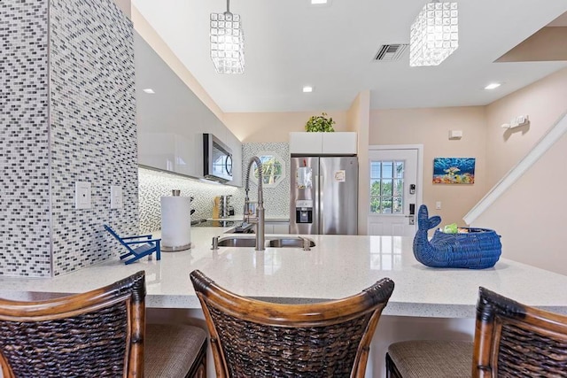 kitchen featuring pendant lighting, decorative backsplash, sink, stainless steel appliances, and white cabinets