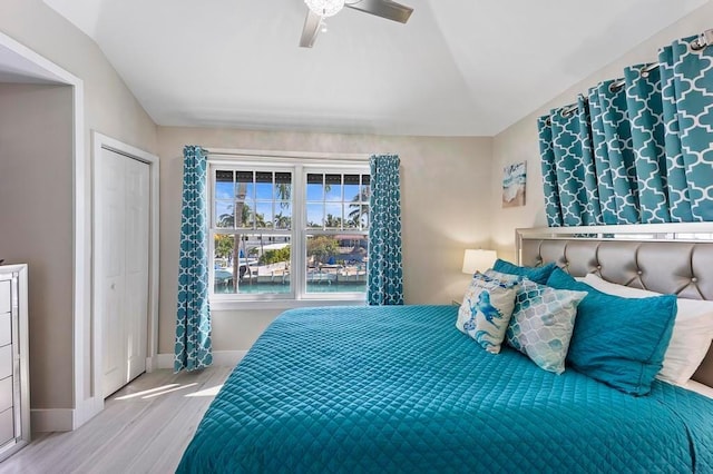 bedroom featuring ceiling fan, light wood-type flooring, a closet, and vaulted ceiling