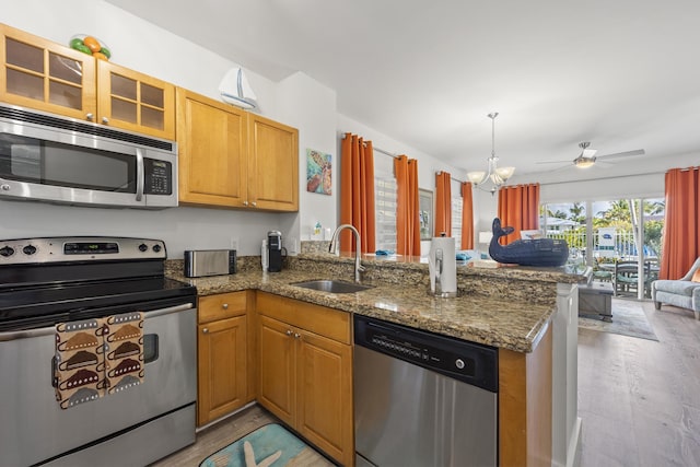 kitchen with ceiling fan with notable chandelier, sink, appliances with stainless steel finishes, and kitchen peninsula