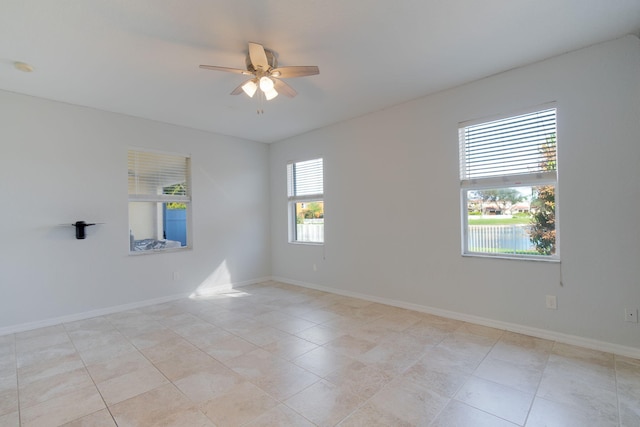 tiled empty room with ceiling fan and a wealth of natural light