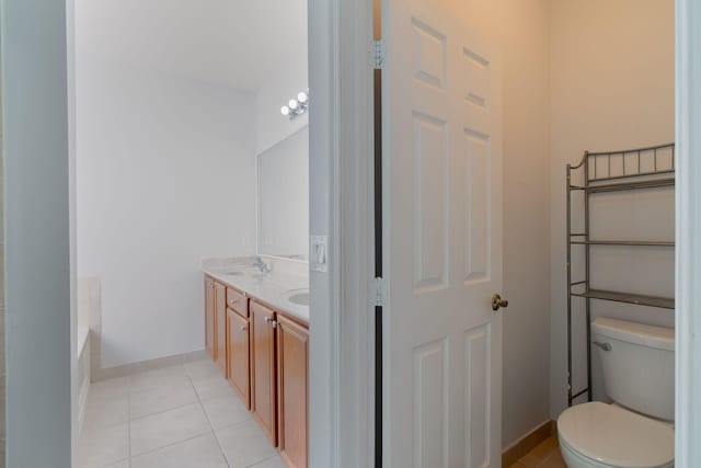 bathroom featuring toilet, vanity, tile patterned floors, and a bath