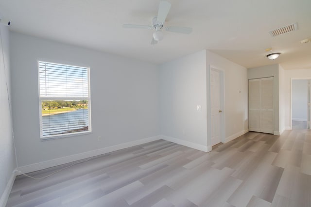 empty room with ceiling fan and light hardwood / wood-style flooring