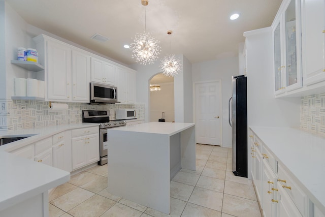 kitchen featuring decorative light fixtures, a kitchen island, white cabinetry, stainless steel appliances, and a chandelier