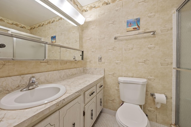 bathroom with a shower with shower door, toilet, vanity, and tile patterned flooring